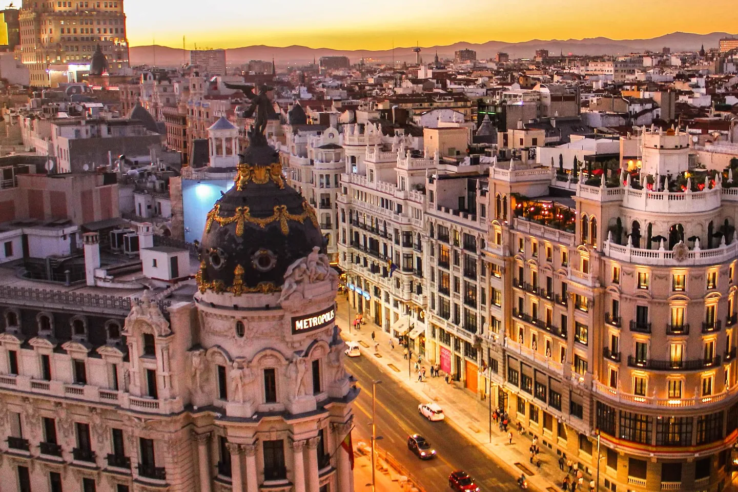 La Gran Vía de Madrid desde arriba al atardecer, con el edificio Metropolis en primer plano